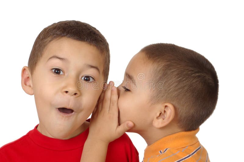 Two boys, aged five and six years, share a secret as one whispers in the other's ear, isolated on white background. Two boys, aged five and six years, share a secret as one whispers in the other's ear, isolated on white background