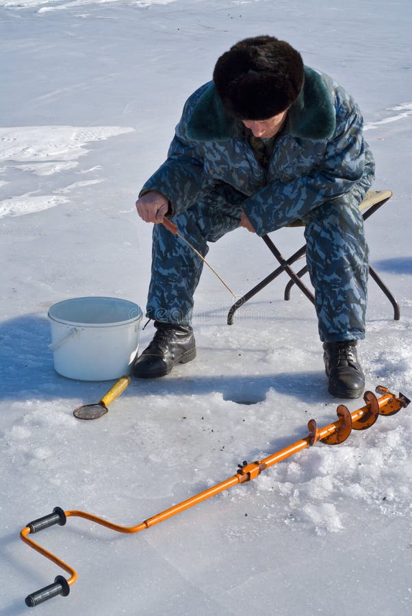 A man on winter fishing on ice of river. A man on winter fishing on ice of river.