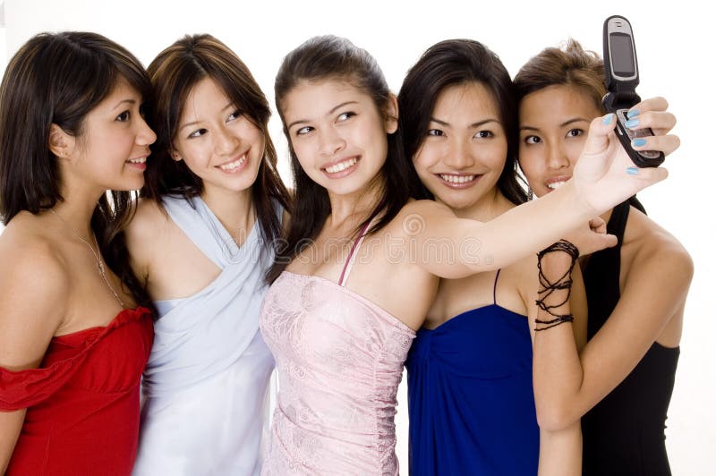 Five attractive young asian women in evening wear take their photo using a camera phone. Five attractive young asian women in evening wear take their photo using a camera phone