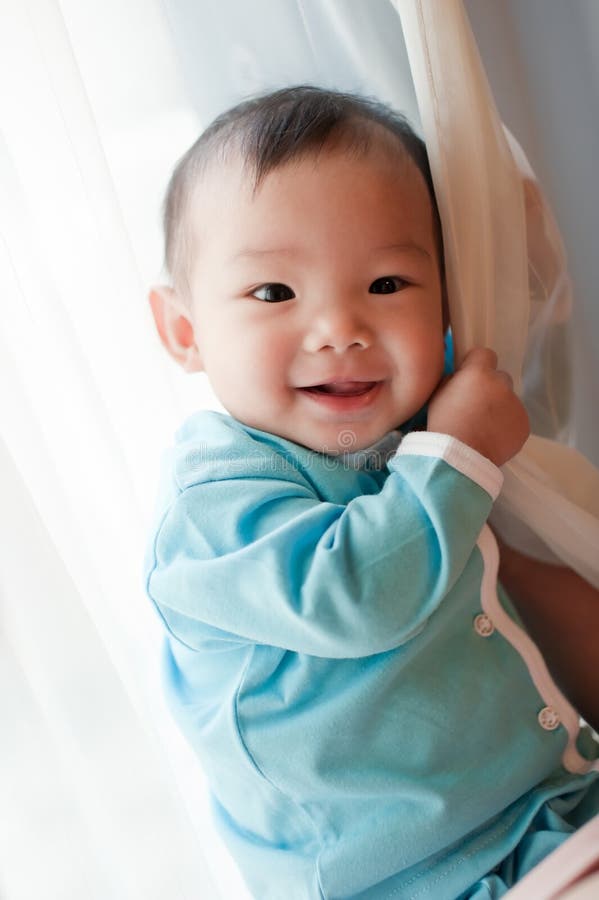 7 month old Asian baby girl smiling and holding on