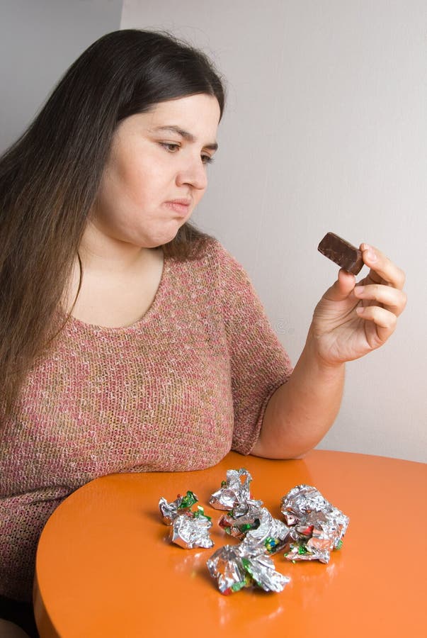 Stout woman contemplating over wrappers of sweets. Stout woman contemplating over wrappers of sweets