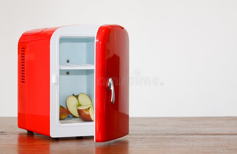 Shiny bright red miniature fridge with apple cut in three parts in it. Shiny bright red miniature fridge with apple cut in three parts in it