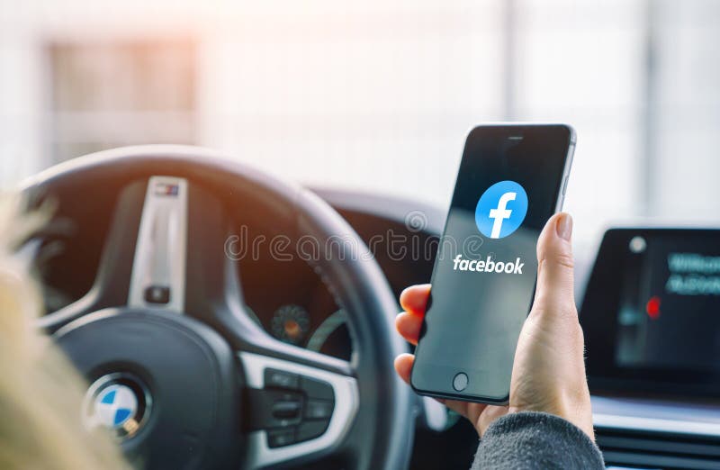 AACHEN, ALLEMAGNE AOÛT 2019 : Femme tenant un iPhone d'Apple ouvrant une application Facebook dans une voiture Facebook est le pl image stock AACHEN, ALLEMAGNE AOÛT 2019 : Femme tenant un iPhone d'Apple ouvrant une application Facebook dans une voiture Facebook est le pl image stock
