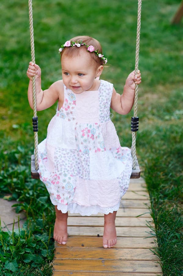 Aanbiddelijk babymeisje die van een schommelingsrit op een speelplaats in een park genieten