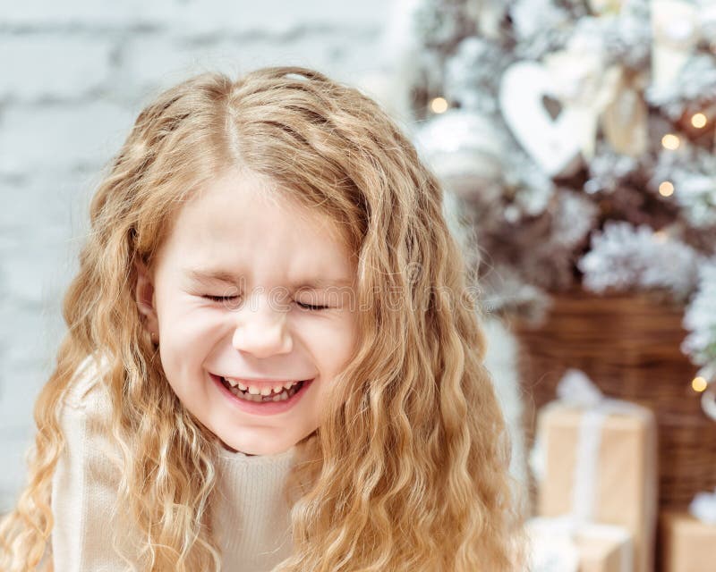 Aanbiddelijk blond meisje die met gesloten ogen, Kerstmis lachen stock fotografie Aanbiddelijk blond meisje die met gesloten ogen, Kerstmis lachen stock fotografie