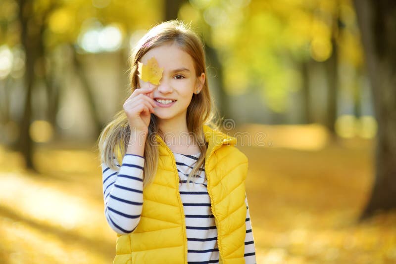 Aanbiddelijk jong meisje die pret op mooie de herfstdag hebben Het gelukkige kind spelen in de herfstpark Jong geitje die geel da stock fotografie Aanbiddelijk jong meisje die pret op mooie de herfstdag hebben Het gelukkige kind spelen in de herfstpark Jong geitje die geel da stock fotografie