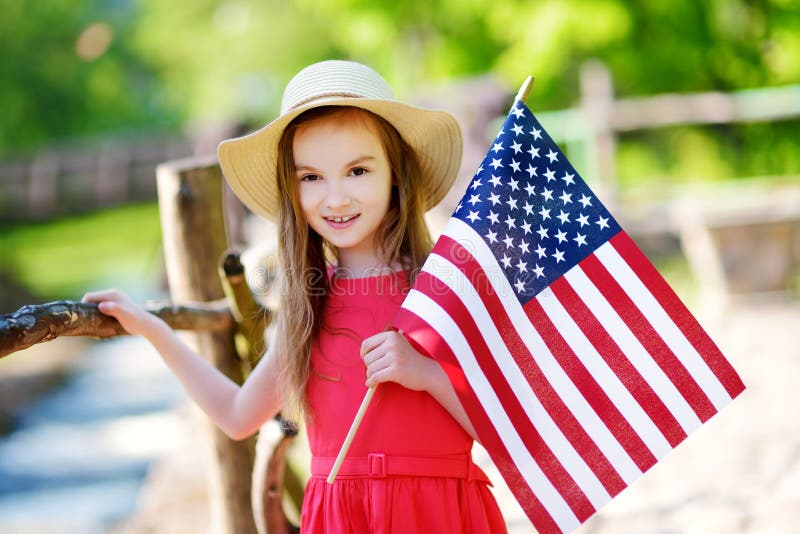 Aanbiddelijk meisje die hoed dragen die Amerikaanse vlag in openlucht op mooie de zomerdag houden royalty-vrije stock fotografie Aanbiddelijk meisje die hoed dragen die Amerikaanse vlag in openlucht op mooie de zomerdag houden royalty-vrije stock fotografie