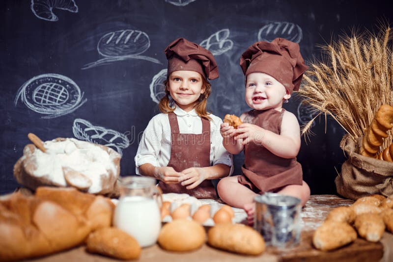 Aanbiddelijk meisje met kind bij lijst het koken stock foto's Aanbiddelijk meisje met kind bij lijst het koken stock foto's