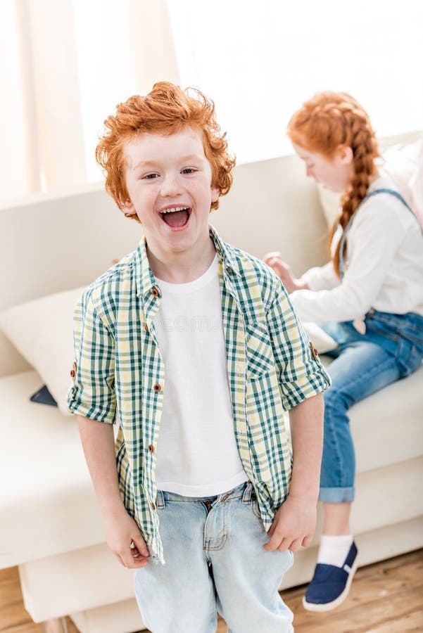 Aanbiddelijk portret van weinig jongen die terwijl weinig zuster die op bank spelen lachen stock fotografie Aanbiddelijk portret van weinig jongen die terwijl weinig zuster die op bank spelen lachen stock fotografie