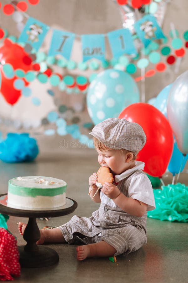 Aanbiddelijke gelukkige babyjongen die cake eten bij zijn eerste verjaardags cakesmash partij royalty-vrije stock foto's Aanbiddelijke gelukkige babyjongen die cake eten bij zijn eerste verjaardags cakesmash partij royalty-vrije stock foto's
