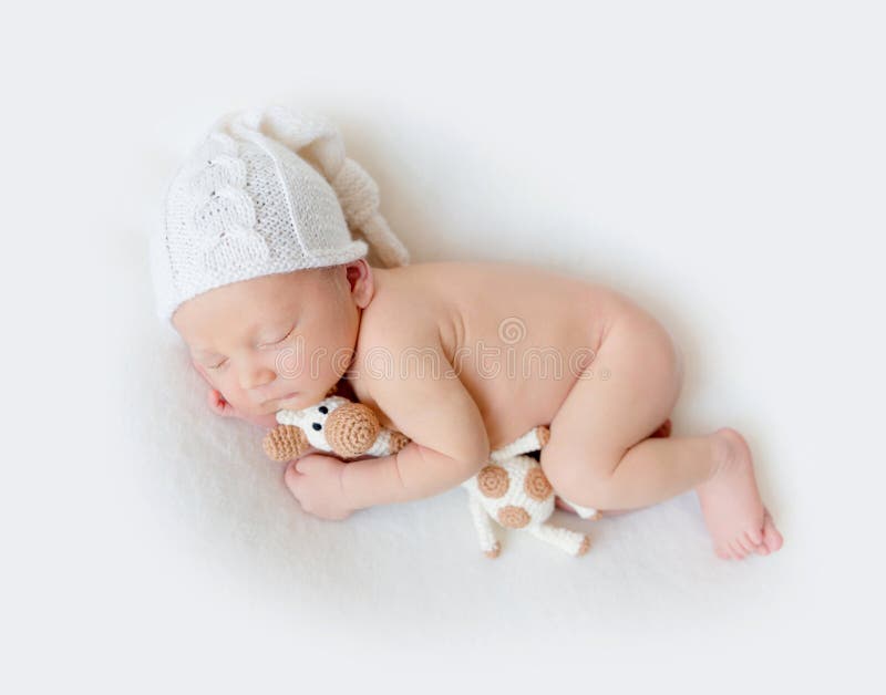 Aanbiddelijke pasgeboren babyslaap die een stuk speelgoed houden stock fotografie Aanbiddelijke pasgeboren babyslaap die een stuk speelgoed houden stock fotografie
