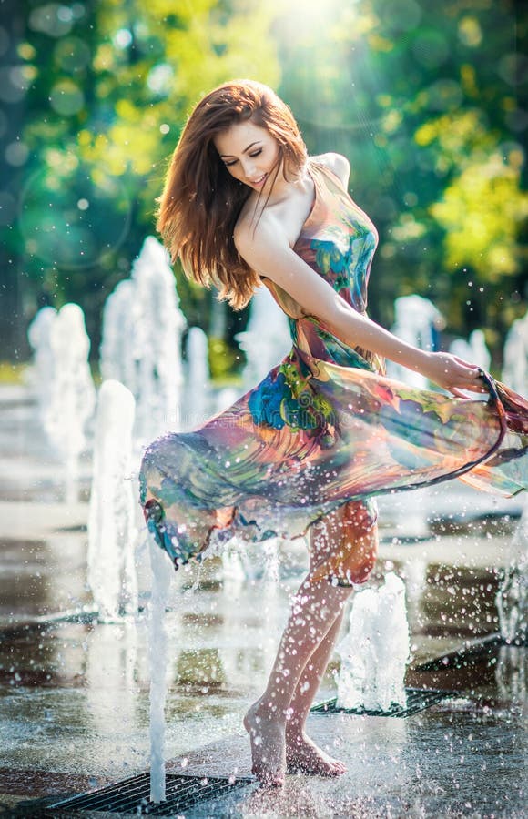 Aantrekkelijk meisje in het multicolored korte kleding spelen met water in een de zomer heetste dag Meisje die met natte kleding
