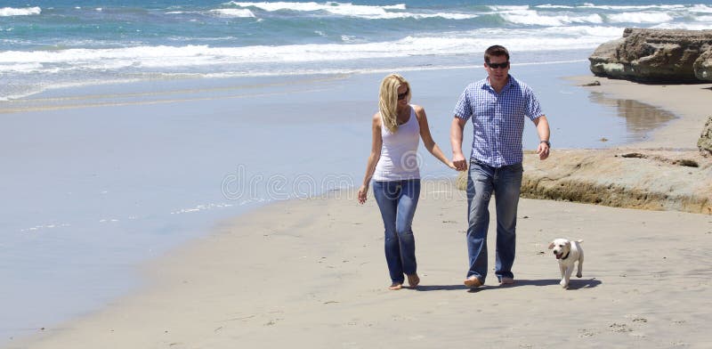 Aantrekkelijk Paar die bij het Strand met Hun Puppy lopen royalty-vrije stock afbeeldingen Aantrekkelijk Paar die bij het Strand met Hun Puppy lopen royalty-vrije stock afbeeldingen