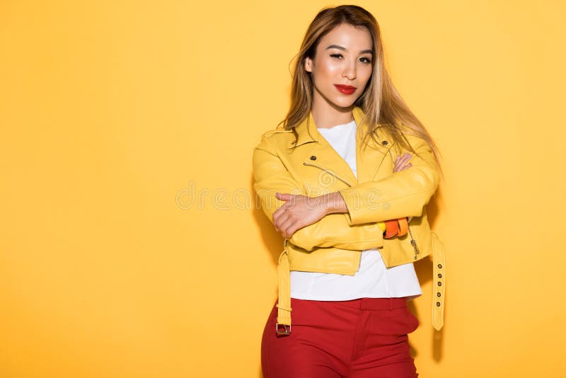 aantrekkelijke jonge Aziatische vrouw in leerjasje het stellen op geel stock foto aantrekkelijke jonge Aziatische vrouw in leerjasje het stellen op geel stock foto