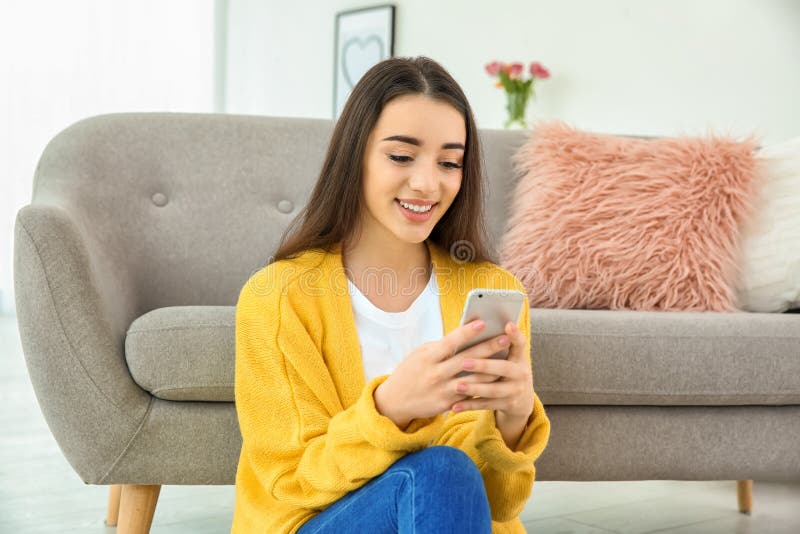 Aantrekkelijke jonge vrouw die mobiele telefoon met behulp van dichtbij bank royalty-vrije stock afbeelding Aantrekkelijke jonge vrouw die mobiele telefoon met behulp van dichtbij bank royalty-vrije stock afbeelding