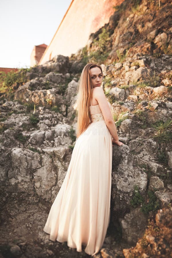 Aantrekkelijke jonge vrouw in lange kleding die zich op de rotsen bevinden royalty-vrije stock foto's Aantrekkelijke jonge vrouw in lange kleding die zich op de rotsen bevinden royalty-vrije stock foto's