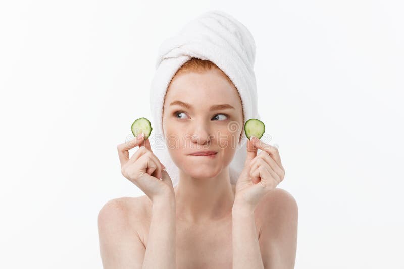 Attractive Young Woman with beautiful clean skin. White mask and cucumbers. Beauty treatments and cosmetology spa therapy. White background. Attractive Young Woman with beautiful clean skin. White mask and cucumbers. Beauty treatments and cosmetology spa therapy. White background.