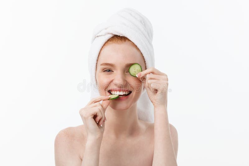 Attractive Young Woman with beautiful clean skin. White mask and cucumbers. Beauty treatments and cosmetology spa therapy. White background. Attractive Young Woman with beautiful clean skin. White mask and cucumbers. Beauty treatments and cosmetology spa therapy. White background.