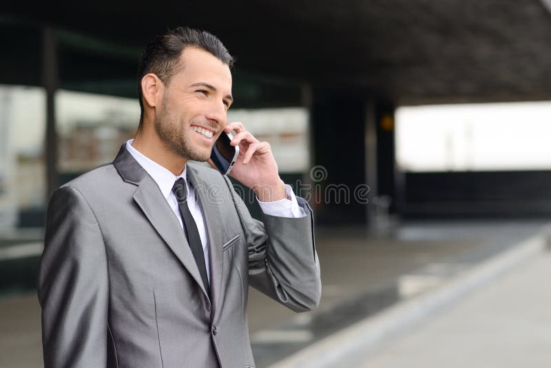 Aantrekkelijke jonge zakenman op de telefoon in een bureaugebouw