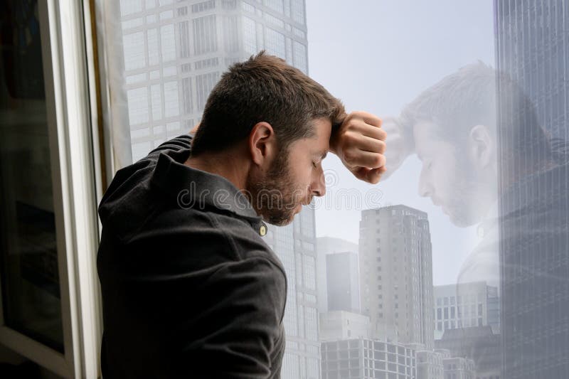 Aantrekkelijke mens die op bedrijfsdistrictsvenster leunen die aan emotionele crisis en depressie lijden stock foto's Aantrekkelijke mens die op bedrijfsdistrictsvenster leunen die aan emotionele crisis en depressie lijden stock foto's