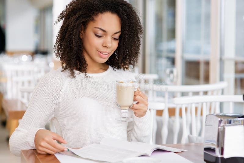 Aantrekkelijke vrouw die een tijdschrift lezen terwijl het drinken royalty-vrije stock foto Aantrekkelijke vrouw die een tijdschrift lezen terwijl het drinken royalty-vrije stock foto