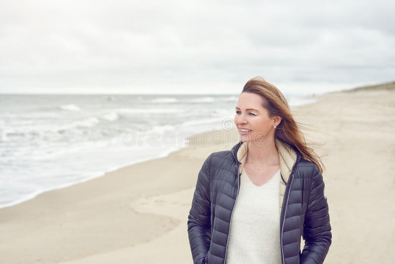 Aantrekkelijke in vrouw die op een verlaten zandig strand lopen royalty-vrije stock foto Aantrekkelijke in vrouw die op een verlaten zandig strand lopen royalty-vrije stock foto