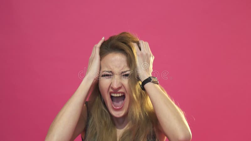 Aantrekkelijke vrouw die in paniek met haar handen aan haar hoofd, mond open en bang gemaakte wijd open ogen gillen