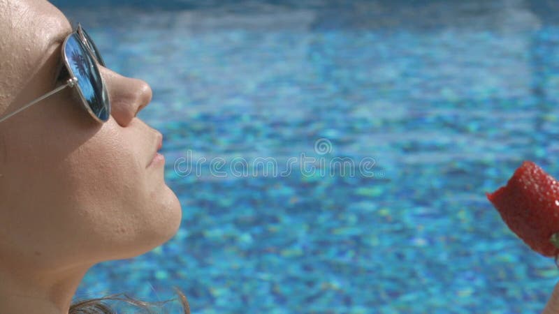 Aantrekkelijke vrouw die seductively zoete aardbei eten dichtbij pool, de zomerflirt