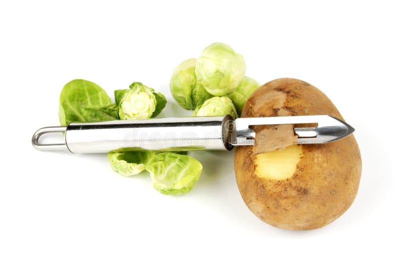 Small brown raw potato with chrome peeler and peeled green sprouts on a reflective white background. Small brown raw potato with chrome peeler and peeled green sprouts on a reflective white background