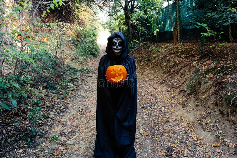 Jovem Mulher Com Máscara De Pintura De Halloween Vestindo Bruxa Negra  Assustadora Segurando Abóbora-macaca Imagem de Stock - Imagem de carnaval,  feriado: 195637671