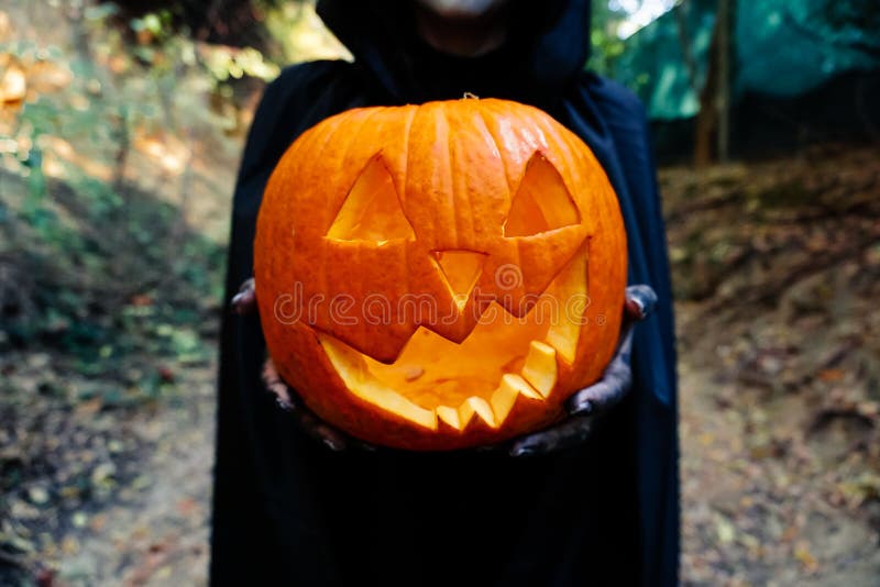 Jovem Mulher Com Máscara De Pintura De Halloween Vestindo Bruxa Negra  Assustadora Segurando Abóbora-macaca Imagem de Stock - Imagem de carnaval,  feriado: 195637671