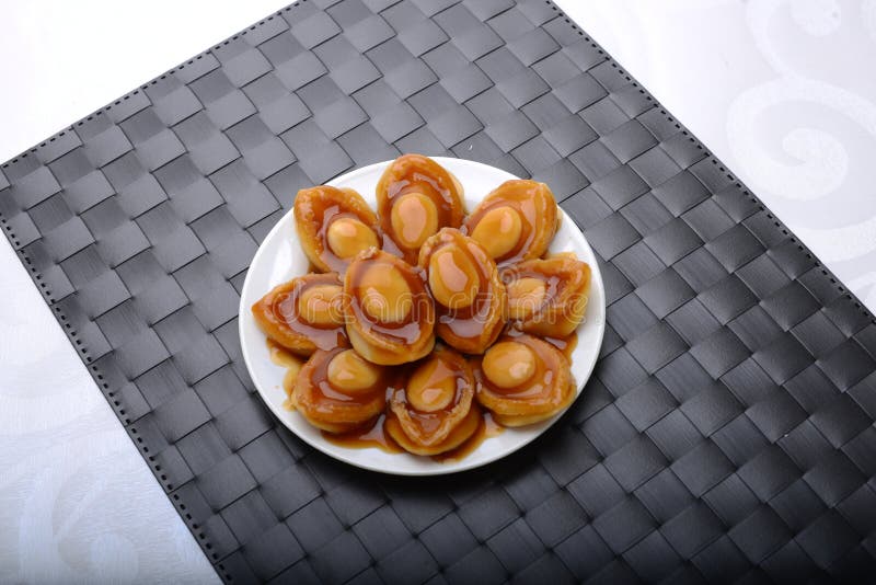 Abalone servings in a fine dining setting on black table mat