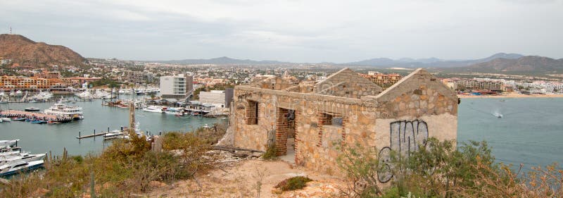 Abandoned brick and stone building on hill above Cabo San Lucas marina and harbor in Baja California Mexico