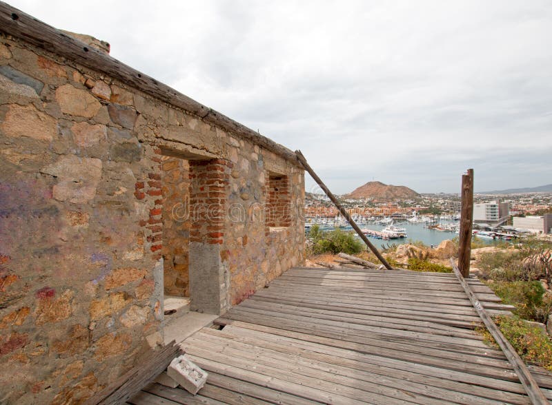 Abandoned brick and stone building on hill above Cabo San Lucas marina and harbor in Baja California Mexico