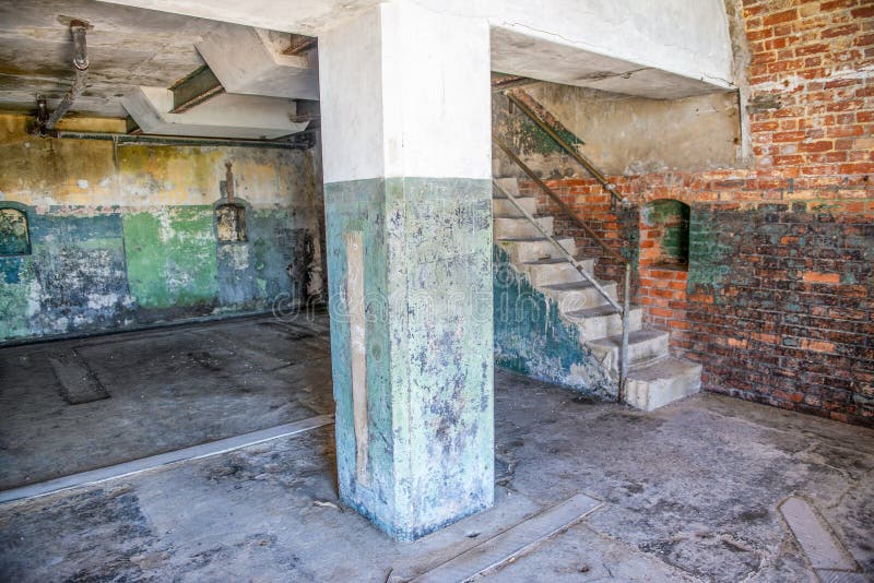 Abandoned building interior with stairs and column. Brick wall