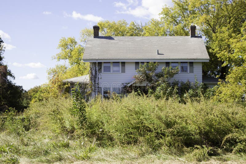 Koloniální styl dům je přerostlý plevele křoví vzhled na být opuštěný.