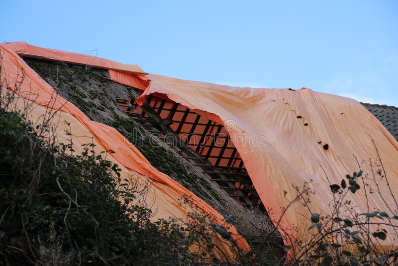 Abandoned farm in the netherlands with orange sheet in attempt to keep rain out stock photo Abandoned farm in the netherlands with orange sheet in attempt to keep rain out stock photo