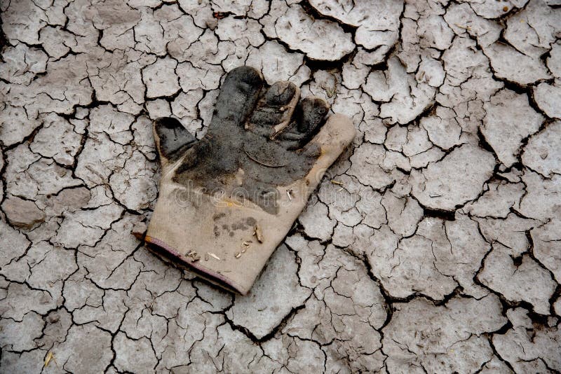 A pair of abandoned old gloves on dry mud background. Pair working gloves stock images, royalty-free photos and pictures