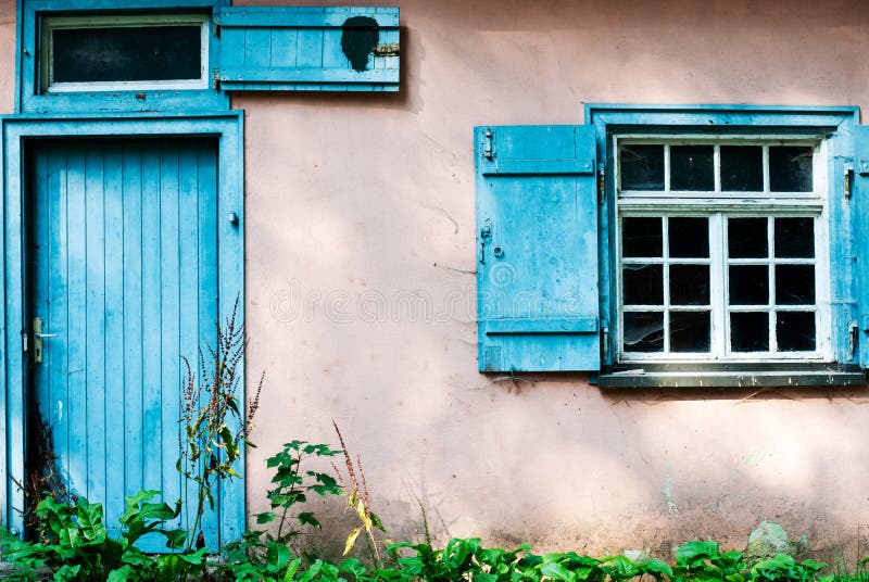 Abandoned house with blue wooden door and shutter