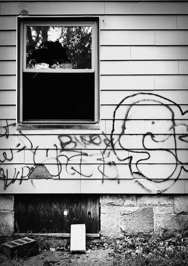 Abandoned house with broken window and graffiti.