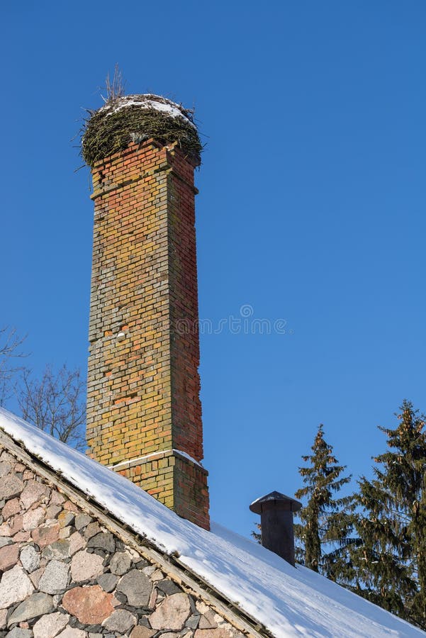Abandoned ruin of oven chimney. Broken furnace. Snowy roof, stork slot and blue sky background in the winter. royalty free stock photos Abandoned ruin of oven chimney. Broken furnace. Snowy roof, stork slot and blue sky background in the winter. royalty free stock photos