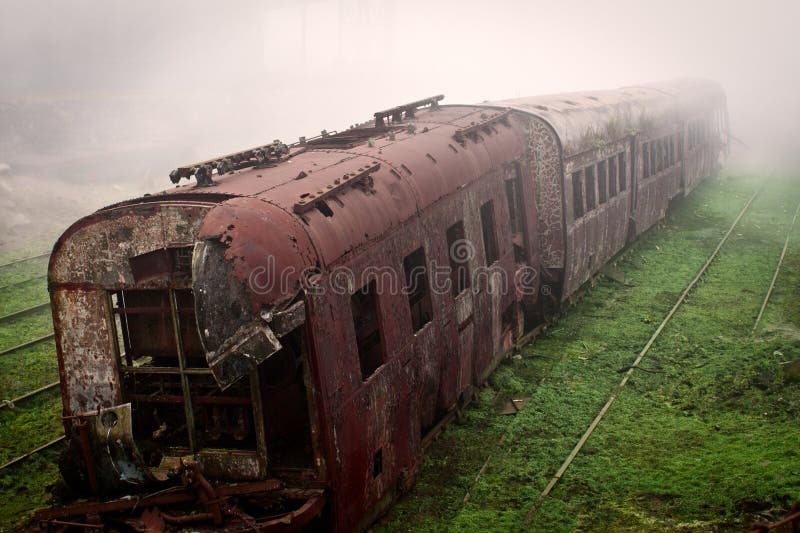 Abandoned rusting train and empty train tracks photographed in a foggy day