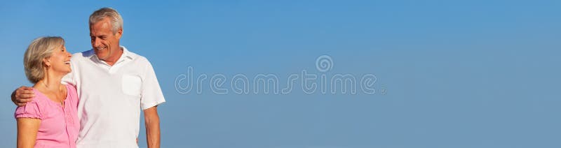 Abarcamiento que camina de los pares mayores felices en panorama del cielo azul foto de archivo