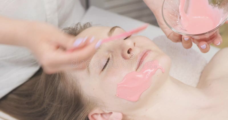 Abbellire una maschera di alginato alla faccia del paziente. una ragazza in un salone di bellezza sta curando la bellezza.