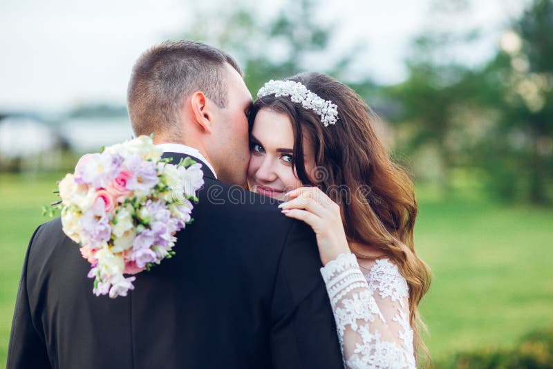 Abbracciare sorridente stupefacente delle coppie di nozze Sposa graziosa e sposo alla moda fotografia stock libera da diritti Abbracciare sorridente stupefacente delle coppie di nozze Sposa graziosa e sposo alla moda fotografia stock libera da diritti