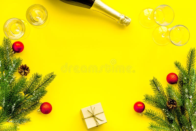 Abeto vermelho, garrafa do champanhe, presente e vidros para a celebração do Natal no modelo amarelo da opinião superior do fundo foto de stock royalty free Abeto vermelho, garrafa do champanhe, presente e vidros para a celebração do Natal no modelo amarelo da opinião superior do fundo foto de stock royalty free