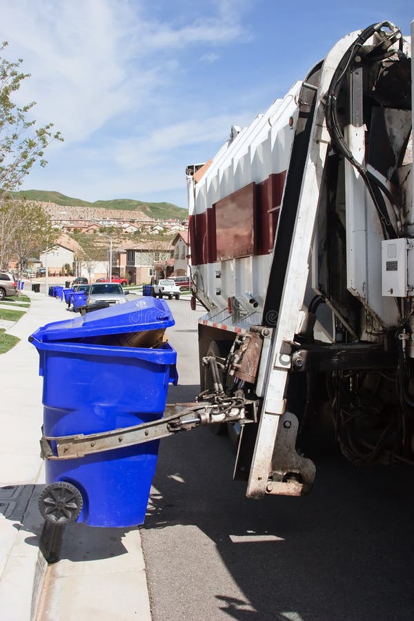 Garbage truck makes a stop to pick the trash bin. Garbage truck makes a stop to pick the trash bin
