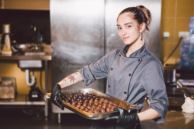 Abhängiges Beruf- und kochengebäck junge kaukasische Frau mit Tätowierung des Patissiers in der Küche des Restaurants Runde vorbe