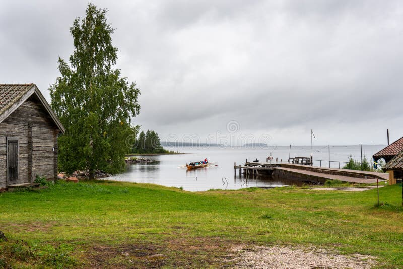Abitanti di una tradizionale barca svedese che si avvicina alla costa in un piccolo villaggio di pescatori vicino al lago Siljan immagine stock libera da diritti Abitanti di una tradizionale barca svedese che si avvicina alla costa in un piccolo villaggio di pescatori vicino al lago Siljan immagine stock libera da diritti