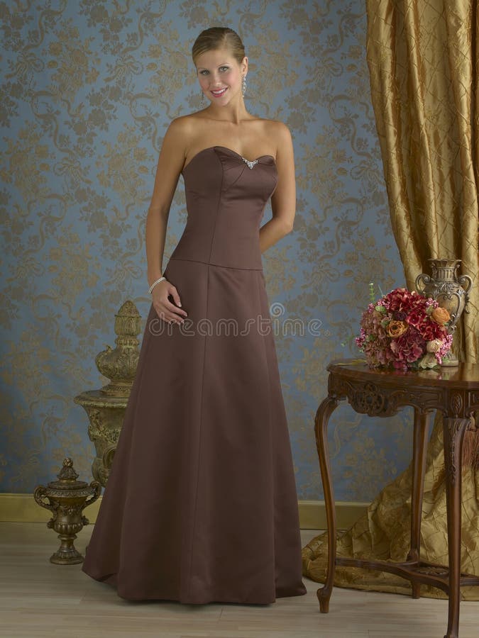 Beautiful blond fashion model wearing long brown evening gown in fancy room setting. Beautiful blond fashion model wearing long brown evening gown in fancy room setting.